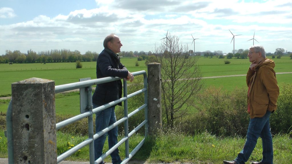 Wethouder Dorus Klomberg in gesprek met dhr. Van Leeuwen, in een weiland vanwege de anderhalve meter afstand.