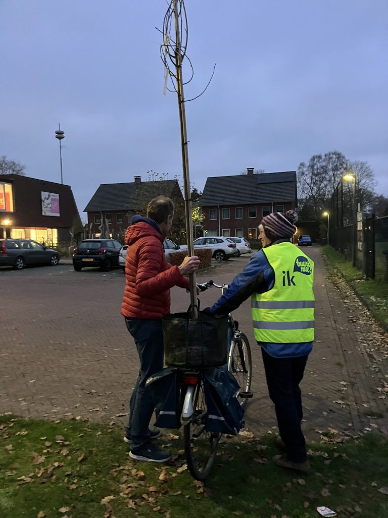 Afbeelding van een inwoner met zijn fiets en achterop een gratis boom die hij kwam afhalen. Een vrijwilliger begeleidt hem